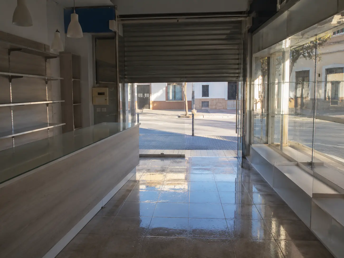 Tienda de calle con la persiana a medio subir a primera hora